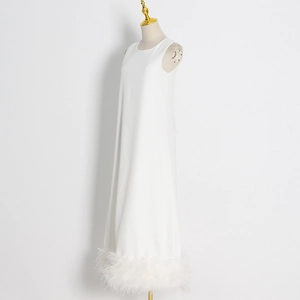 Close-up of elegant white sleeveless dress featuring dense feather trim at the hem