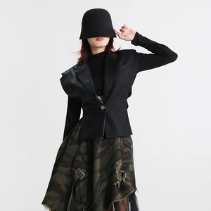 Détail de l'asymétrie du cuir sur une veste sans manches noire ajustée à texture