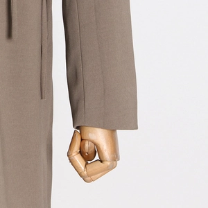 Detail of minimalist cuff and brown suiting fabric on long sleeve blazer with tie design