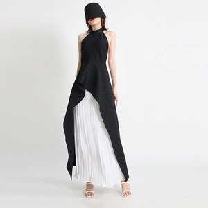 Detail of black halter top with irregular hem paired with white pleated maxi skirt
