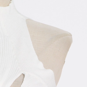 Close-up of the irregular cut-out shoulder detail on a soft white ribbed knit top