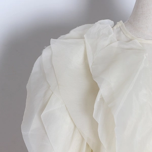 Detail of multi-layered ruffle design on white sheer organza blouse with elegant texture