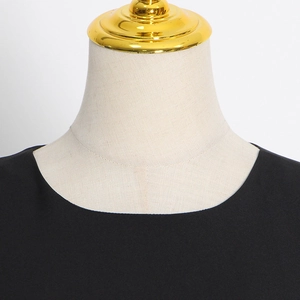 Close-up of minimalist crew neck and textured fabric on a black feather hem dress