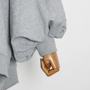 Close-up of gray sweatshirt ribbed cuffs and lantern sleeve detail on a wooden hand model