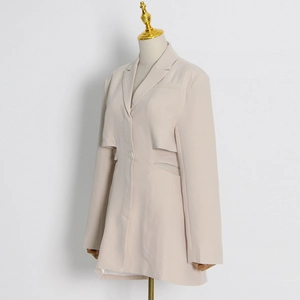 Detail view of waist cut-out and single-button closure on a beige fashion blazer jacket