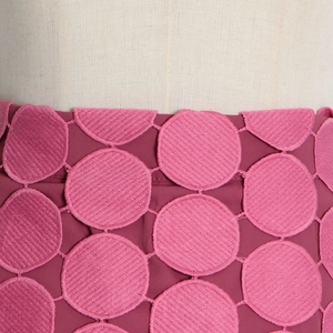 Vue macro de broderies circulaires 3D haute densité sur tissu texturé rose vif