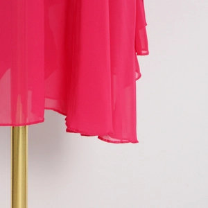 Détail d'une robe en mousseline magenta avec ourlet asymétrique et design multicouche