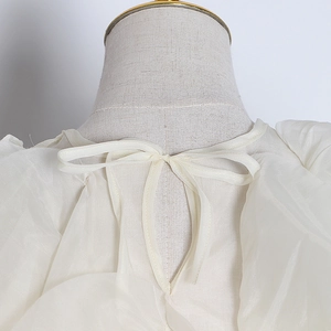 Detail of white organza blouse featuring rear tie bow, cutout back, and puff sleeves