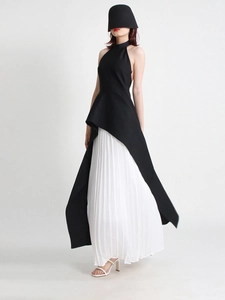 Detail of elegant black halter top with irregular peplum and white pleated maxi skirt
