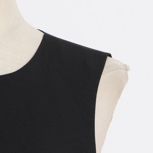 Detailed close-up of a minimalist black sleeveless dress with a clean round neckline