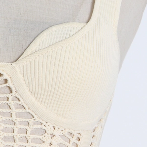 Detailed macro view of the rib-knit texture and handmade crochet stitching on the cream top