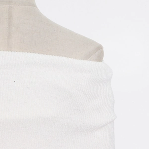 Close-up of white knit dress showing fine vertical ribbed texture and off-shoulder design