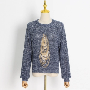 Detail of blue and white knit sweater with cutout design and layered gold chains