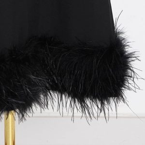 Detail of elegant black ostrich feather trim on the hem of a sleeveless evening dress