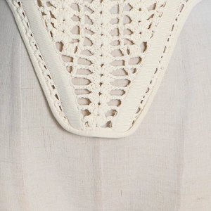 Detailed macro view of cream crochet lace pattern with bohemian hollowed-out texture