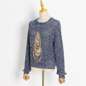 Detail of blue and white knit sweater featuring layered gold metal chain decorations