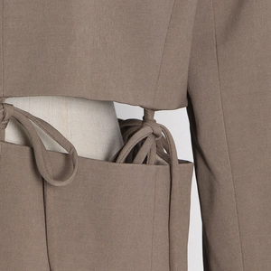 Detailed view of brown suit jacket featuring side cut-out and stylish lace-up straps