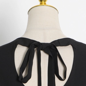 Close-up of the elegant black dress showing neck tie ribbon and backless detail