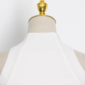 Detailed close-up of premium white knit sleeveless top with ribbed texture and high neck