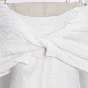Close-up of elegant twist knot design and fine texture on a white knitted shoulder top