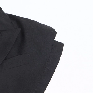 Détail des coutures du tissu sergé noir et du col à revers sur le gilet ajusté