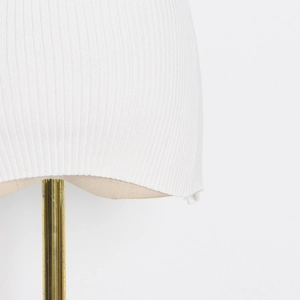 Detailed close-up of white ribbed knit fabric texture and hemline of the slim fit top