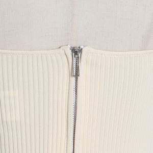 Close-up of smooth metal zipper and ribbed knit fabric on cream corset top