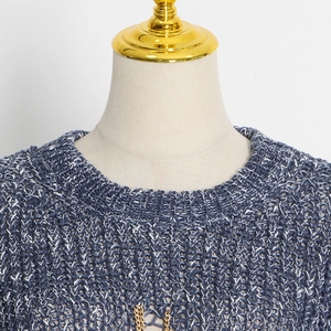 Close-up of blue and white knit sweater with decorative gold chain on the round neck