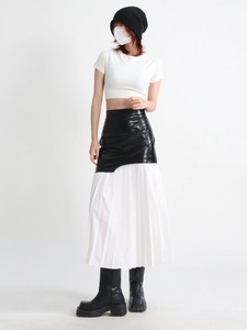 Detail view of high-waisted black leather patchwork with white pleated mesh hem