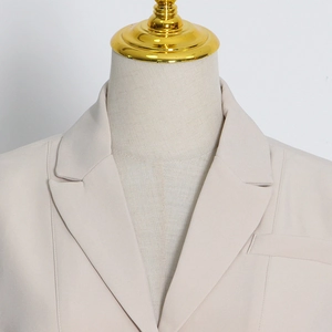 Close-up of lapel and shoulder tailoring on a light beige cutout blazer for women