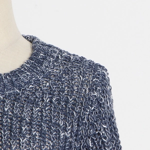 Detail of round neckline and blue-white chunky knit texture on sweater with heavy chain