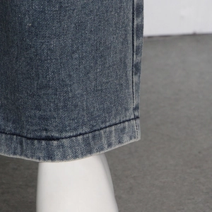 Detailed close-up of dark blue denim hem with double-stitched seams and vintage wash effect
