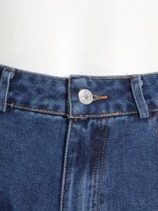 Detalle de la cintura alta de los vaqueros azul oscuro con costuras naranjas y botón