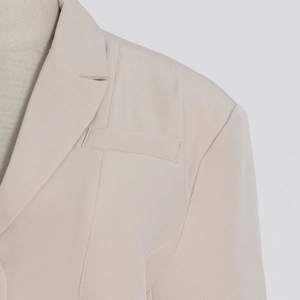 Detail of the notched lapel and shoulder tailoring on a beige fashion blazer jacket