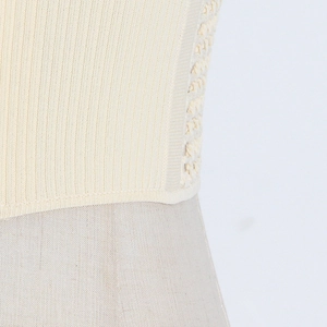 Detail of cream rib-knit vest featuring vertical texture and side braided crochet details