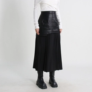 Detail of high waist pleated leather skirt with black mesh patchwork and sleek texture