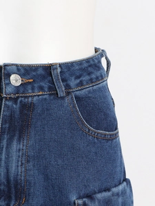 Detalle de los vaqueros de talle alto con costuras naranjas en contraste y botón de metal