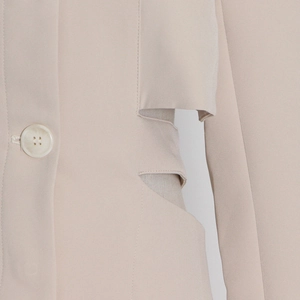 Close-up of beige blazer featuring stylish waist cutout design and textured button detail
