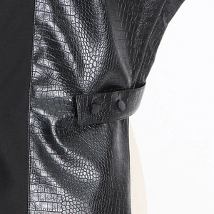 Détail de l'empiècement en cuir crocodile et boutons de réglage sur un gilet noir