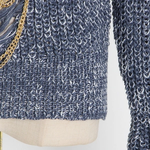 Detail of blue and white knit sweater with gold metal chains and fringe accents