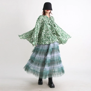 Detail of green abstract print loose shirt with a bow tie neck and layered mesh skirt