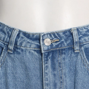 Macro shot of silver metal buttons and stitching on blue denim cargo pants waist