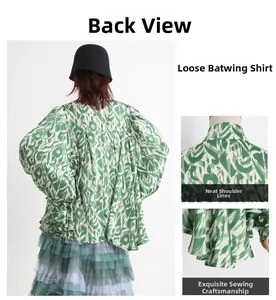Detail view of oversized batwing shirt featuring green abstract print and back pleat