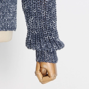 Detail of blue and white knit sweater sleeve featuring thick texture and ribbed cuffs