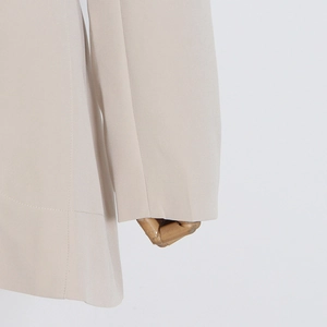 Detail view of high-quality stitching and fabric on a beige cutout waist blazer sleeve