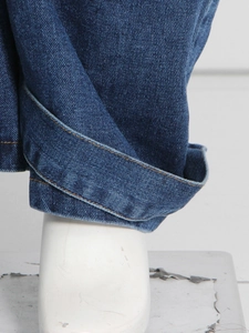 Primer plano del dobladillo doblado de jeans de mezclilla azul con costuras doradas