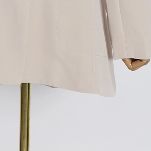 Detailed close-up of beige blazer hem and precise stitching on woven fabric pocket