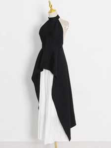 Detail of black halter high-low hem top with white pleated chiffon skirt on mannequin