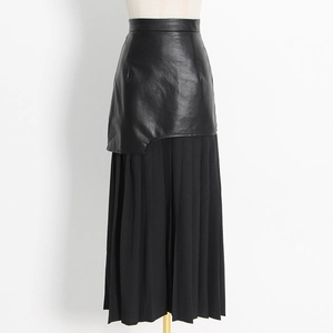 Detail of high-waist pleated long skirt featuring asymmetric black faux leather overlay
