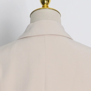 Detail view of the back collar and stitching on a beige cutout waist blazer jacket
